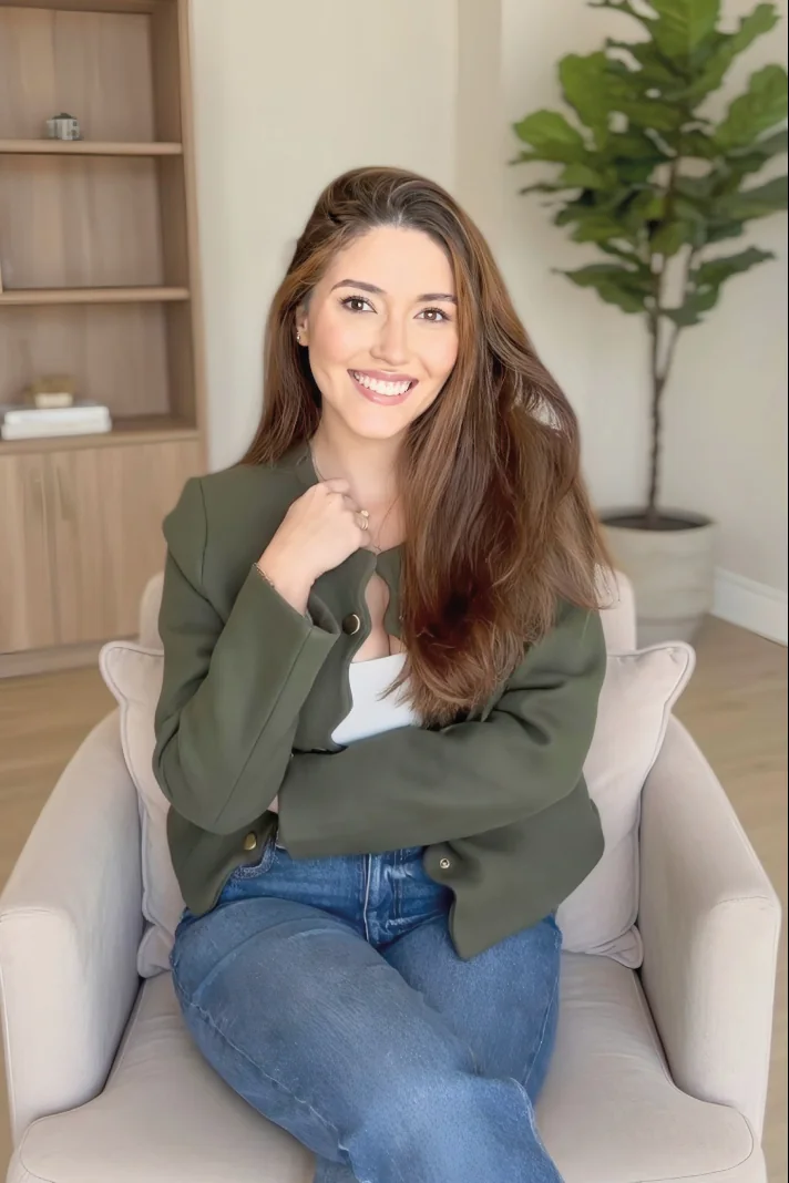 Natália Gomes Klein sentada em uma poltrona clara, sorrindo